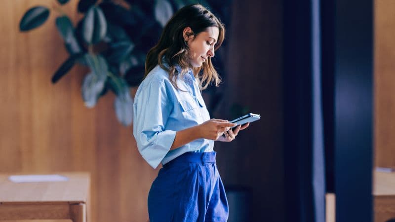 Woman Standing Indoors Using A Tablet Device