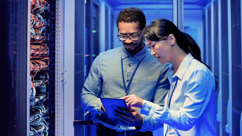 Male And Female IT Engineers Using Digital Tablet In Server Room