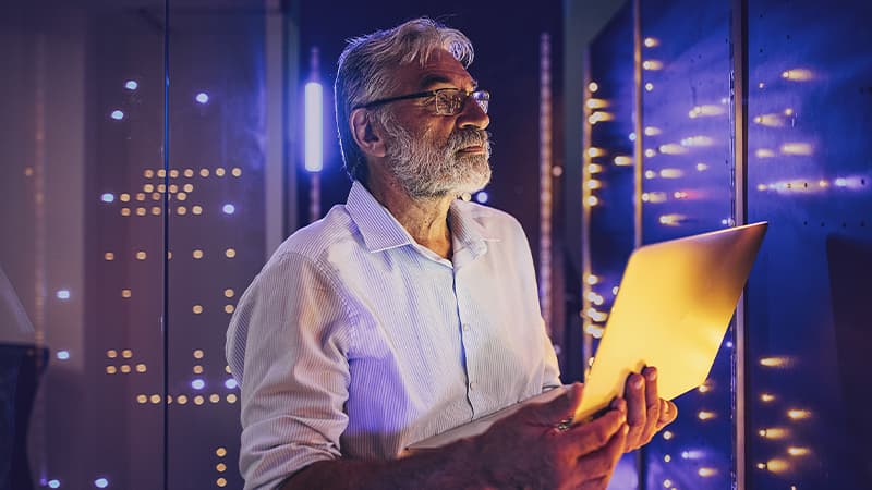 Senior Male Maintenance Engineer Examining Data On Laptop